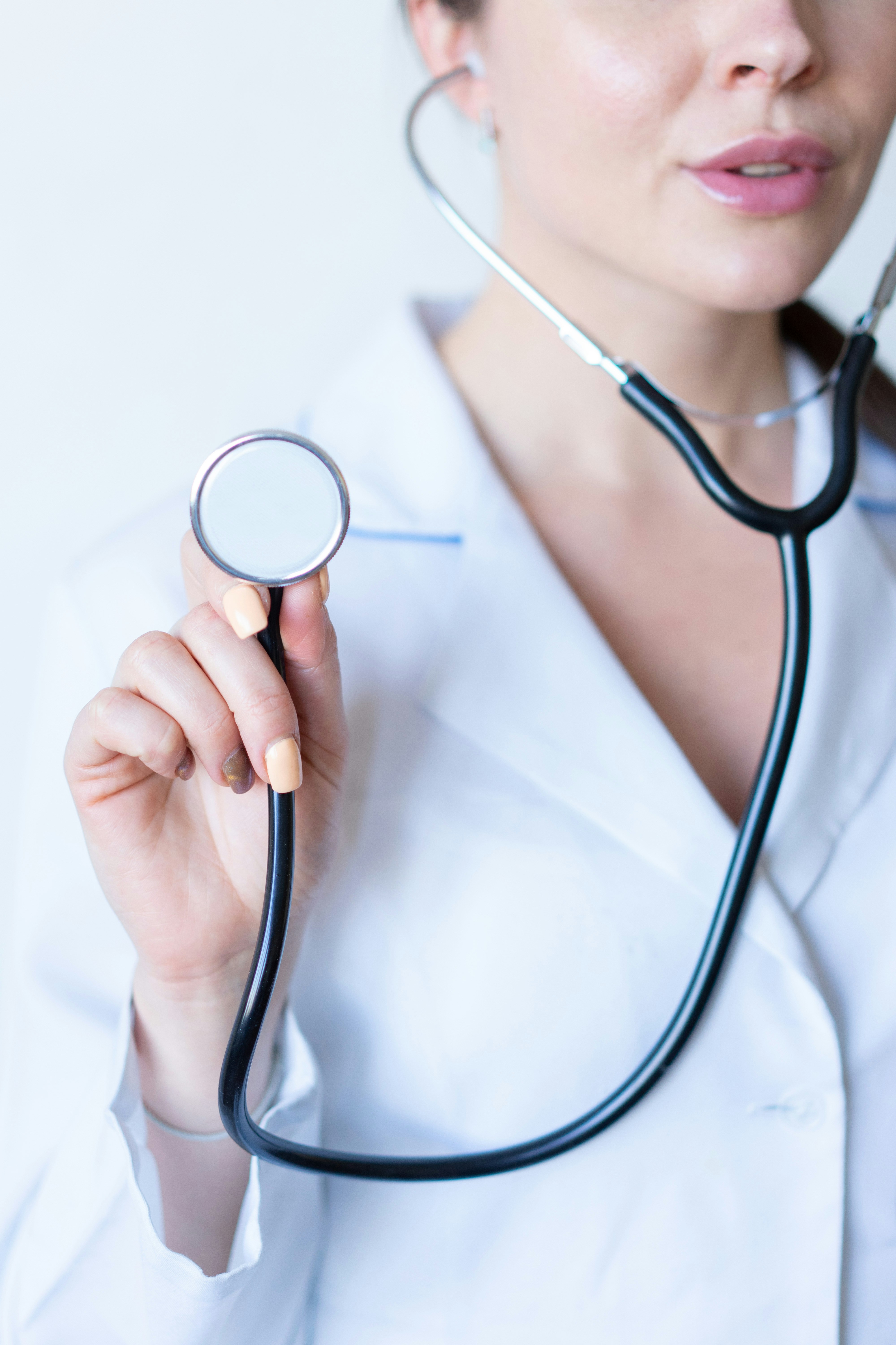 Female doctor with stethoscope in ears and holding base up